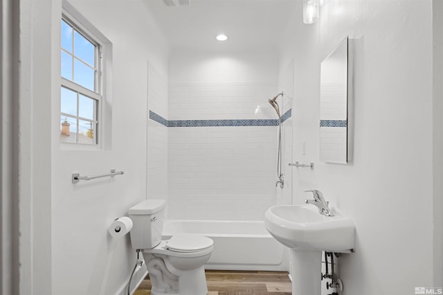 bathroom with toilet, tiled shower / bath combo, and wood-type flooring