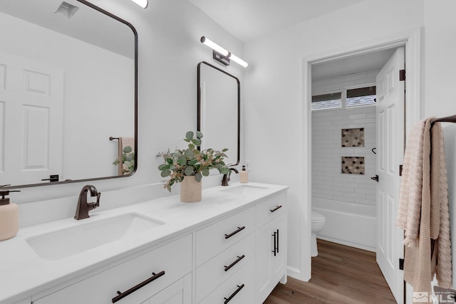 full bathroom featuring vanity, tiled shower / bath combo, hardwood / wood-style flooring, and toilet