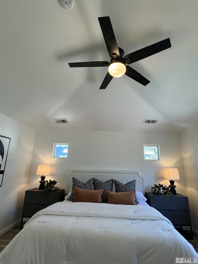 bedroom featuring ceiling fan, a textured ceiling, and dark hardwood / wood-style floors