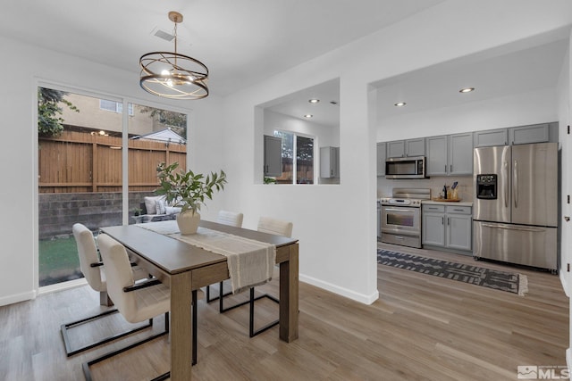 dining area with light hardwood / wood-style flooring and a chandelier