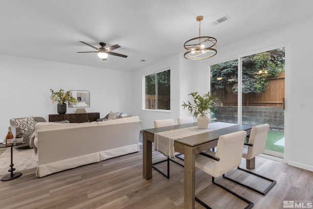 dining area with wood-type flooring and ceiling fan with notable chandelier