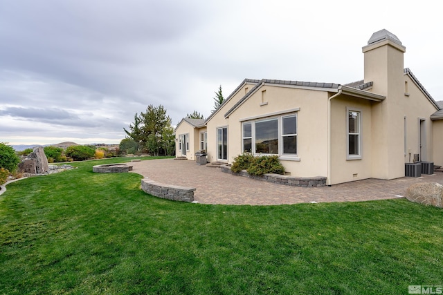 back of property with a yard, cooling unit, and a patio