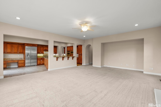 unfurnished living room with light colored carpet and ceiling fan