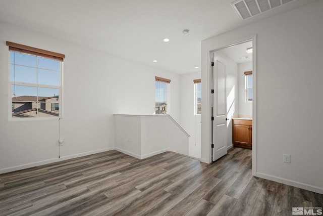 spare room featuring a healthy amount of sunlight and dark hardwood / wood-style flooring