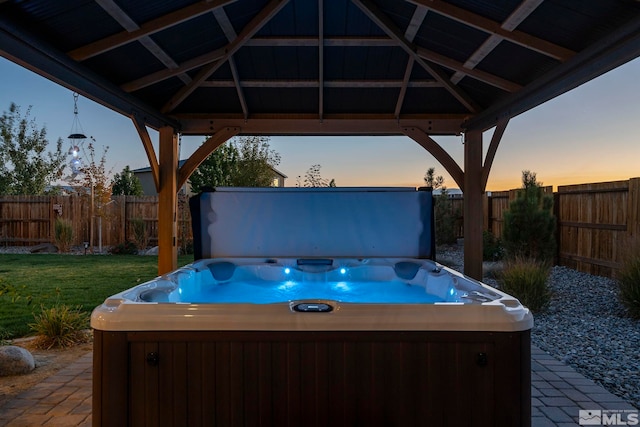 patio terrace at dusk featuring a gazebo and a hot tub