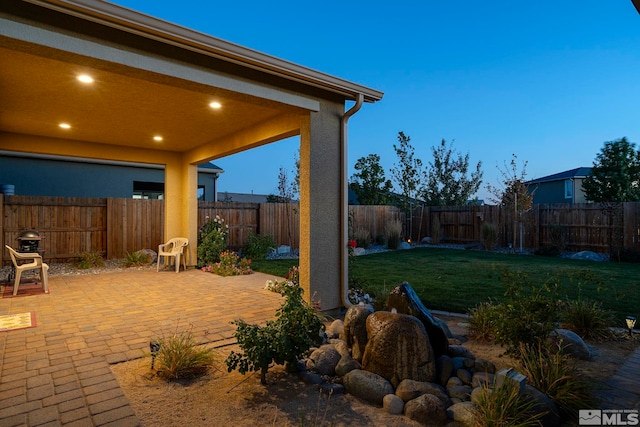 yard at dusk featuring a patio area