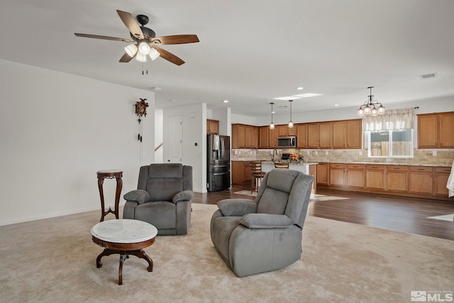 living room featuring light hardwood / wood-style floors, sink, and ceiling fan with notable chandelier