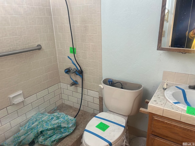 bathroom featuring a tile shower, vanity, and toilet