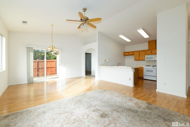 unfurnished living room featuring sink, vaulted ceiling, light hardwood / wood-style flooring, and ceiling fan with notable chandelier