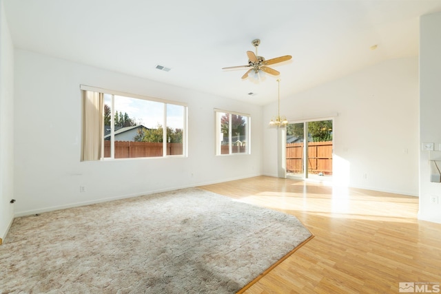 unfurnished room with vaulted ceiling, ceiling fan with notable chandelier, and light wood-type flooring