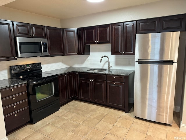 kitchen featuring decorative backsplash, dark brown cabinets, stainless steel appliances, dark stone counters, and sink