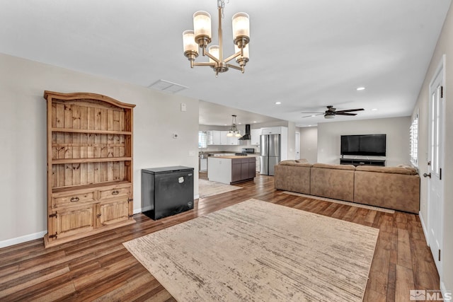 living room featuring ceiling fan with notable chandelier and dark hardwood / wood-style flooring