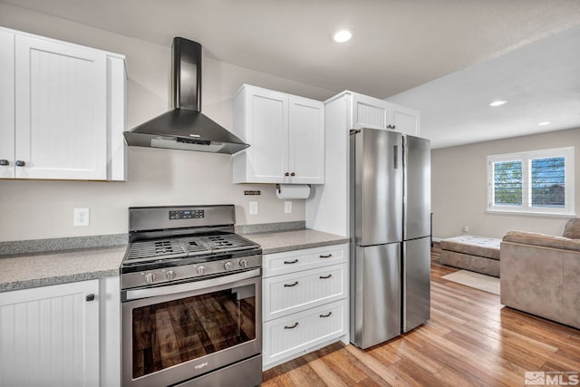 kitchen with white cabinetry, wall chimney range hood, stainless steel appliances, and light hardwood / wood-style floors