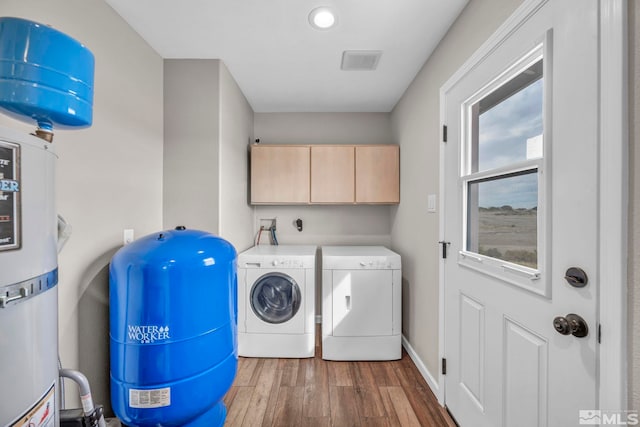 laundry area with water heater, cabinets, separate washer and dryer, and dark hardwood / wood-style floors