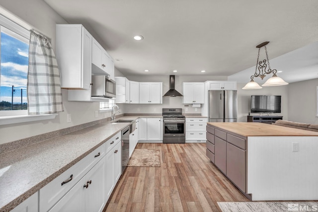 kitchen featuring wall chimney exhaust hood, white cabinetry, stainless steel appliances, and light hardwood / wood-style floors