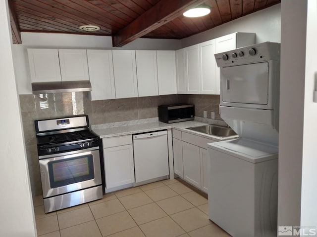 kitchen with stainless steel appliances, beam ceiling, stacked washer and clothes dryer, wooden ceiling, and white cabinets