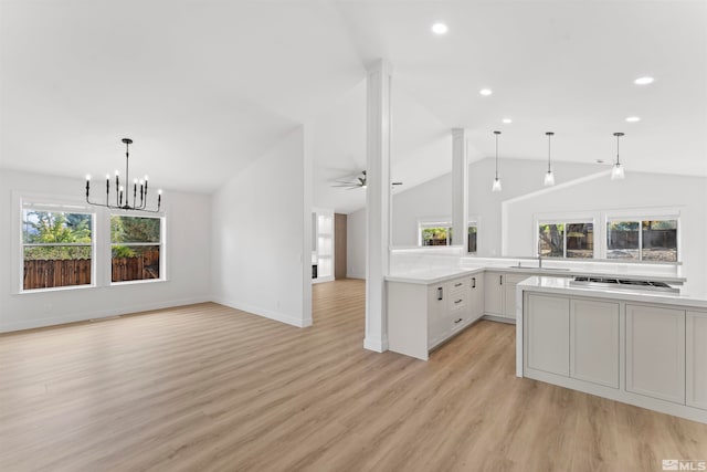 kitchen featuring stainless steel gas stovetop, pendant lighting, vaulted ceiling, white cabinets, and light hardwood / wood-style flooring