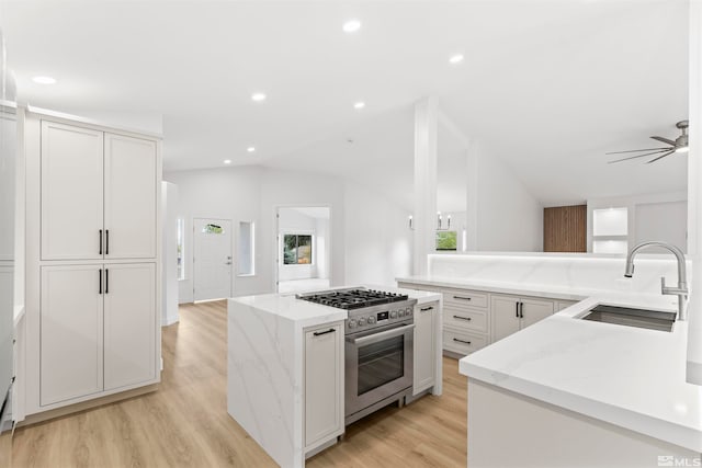 kitchen with high end stainless steel range oven, lofted ceiling, light stone counters, and a center island