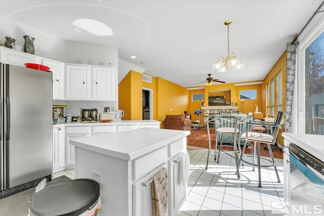 kitchen with appliances with stainless steel finishes, light tile patterned flooring, ceiling fan with notable chandelier, pendant lighting, and white cabinets