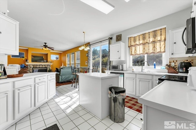 kitchen featuring appliances with stainless steel finishes, a center island, white cabinetry, and decorative light fixtures