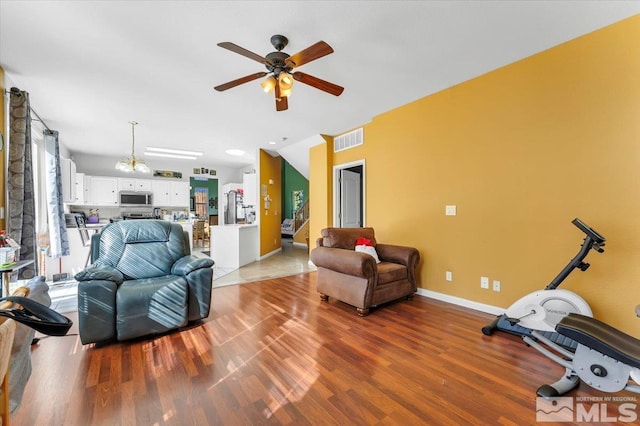 living room with light wood-type flooring and ceiling fan with notable chandelier