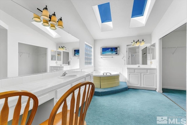 bathroom with vaulted ceiling with skylight, a bathing tub, and vanity