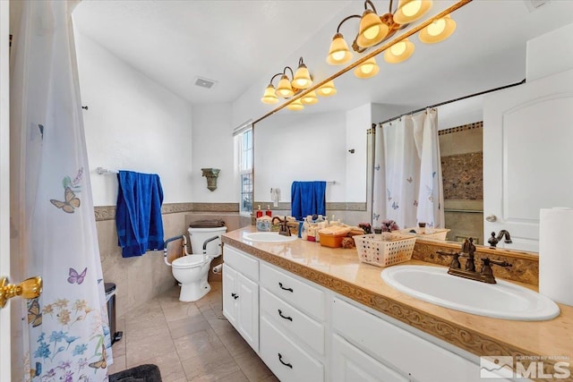 bathroom featuring toilet, tile patterned flooring, vanity, curtained shower, and tile walls