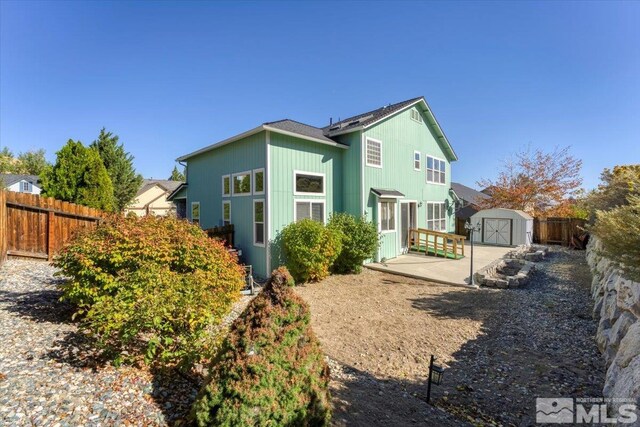 rear view of property with a storage shed