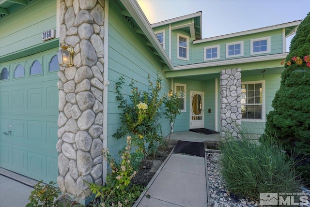 view of exterior entry featuring covered porch and a garage