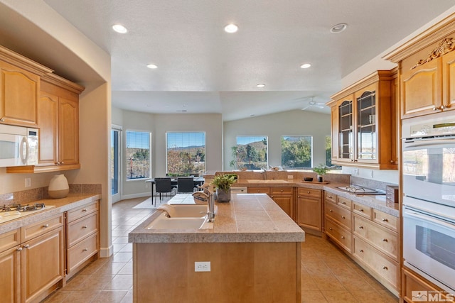 kitchen with lofted ceiling, an island with sink, white appliances, and light tile patterned flooring