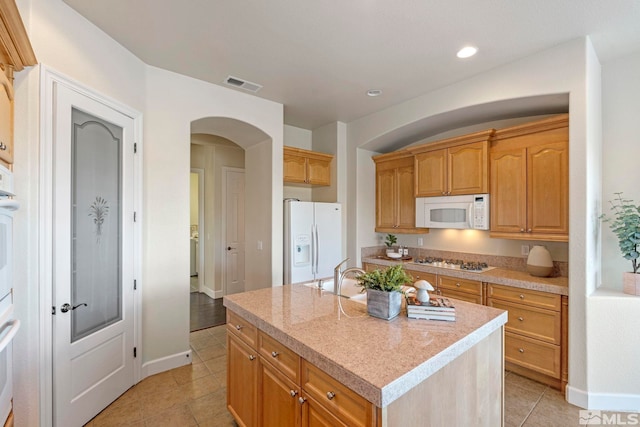 kitchen with a kitchen island with sink, light tile patterned flooring, sink, and white appliances