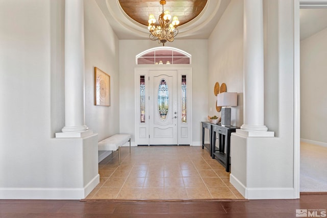 foyer entrance with a notable chandelier, wood-type flooring, and a raised ceiling