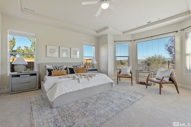 bedroom with ceiling fan, a raised ceiling, and light colored carpet