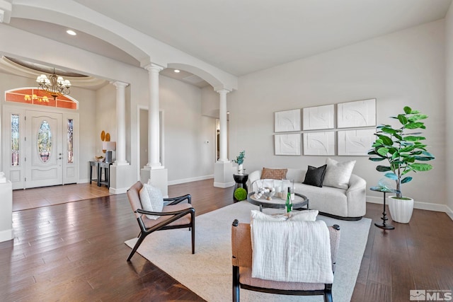 living room featuring an inviting chandelier, wood-type flooring, and decorative columns