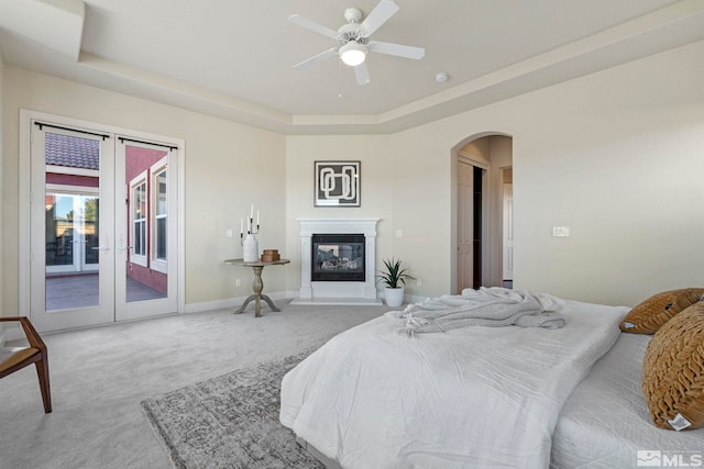 carpeted bedroom featuring access to exterior, a raised ceiling, and ceiling fan