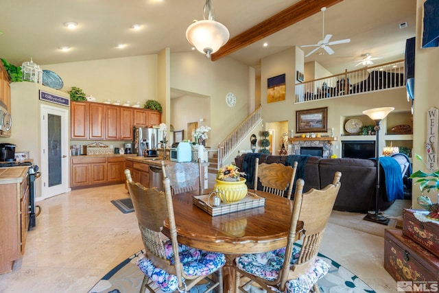 tiled dining room with a towering ceiling, sink, a fireplace, ceiling fan, and beam ceiling