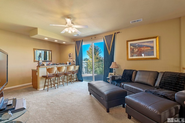 living room featuring ceiling fan, indoor bar, and light colored carpet