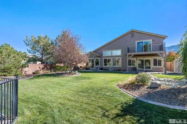 rear view of property with a yard and a balcony