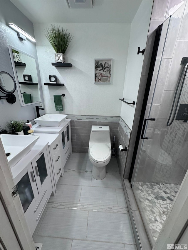 bathroom featuring tile walls, toilet, vanity, an enclosed shower, and tile patterned floors