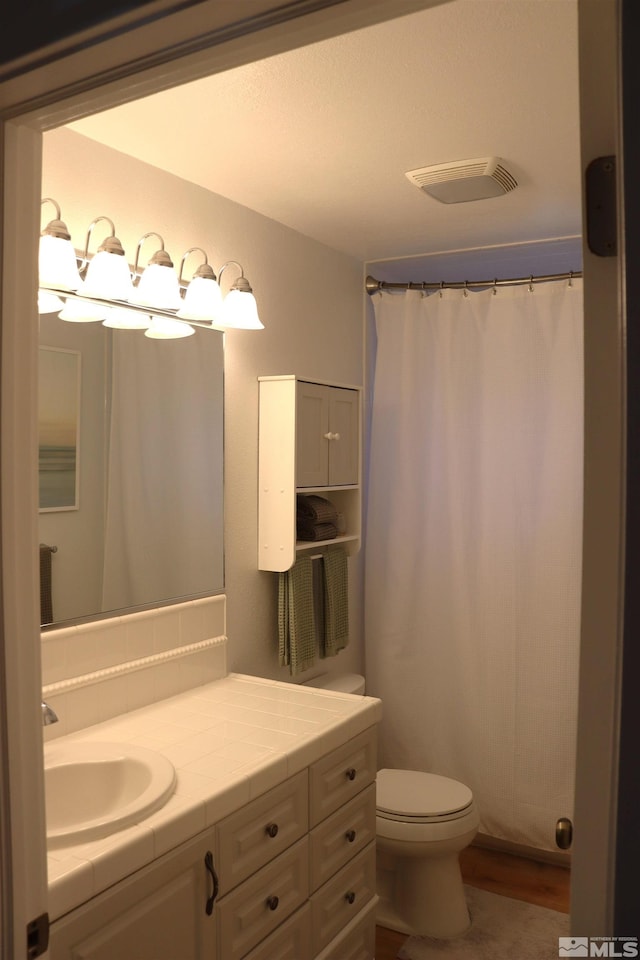 bathroom with toilet, hardwood / wood-style floors, and vanity