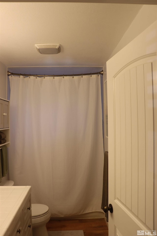 bathroom featuring vanity, toilet, hardwood / wood-style flooring, and walk in shower