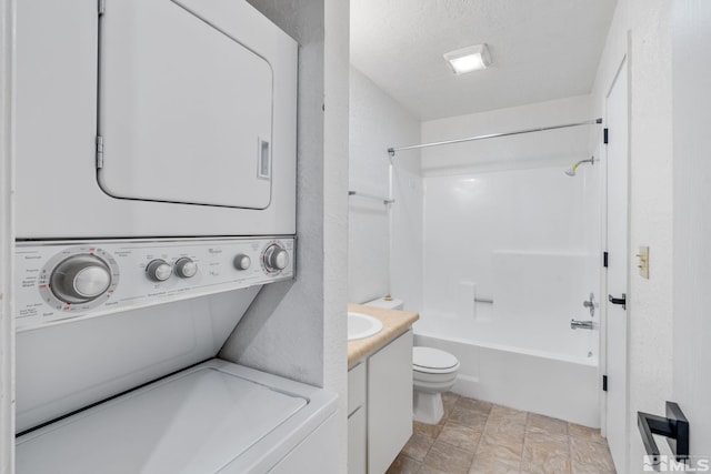 laundry area featuring stacked washer and clothes dryer and a textured ceiling