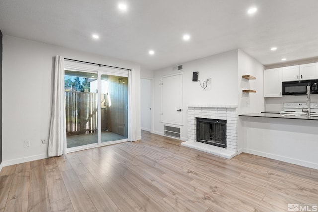 unfurnished living room with a fireplace and light hardwood / wood-style floors