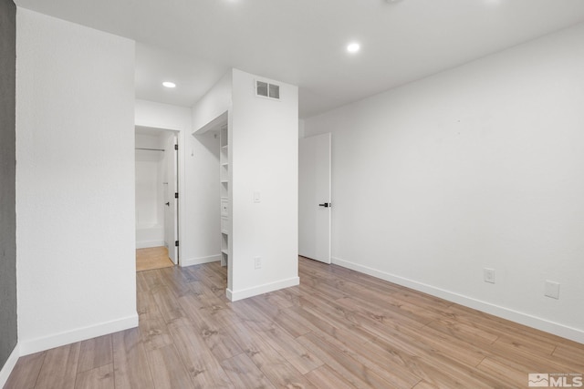 unfurnished bedroom with a closet, light wood-type flooring, and a walk in closet