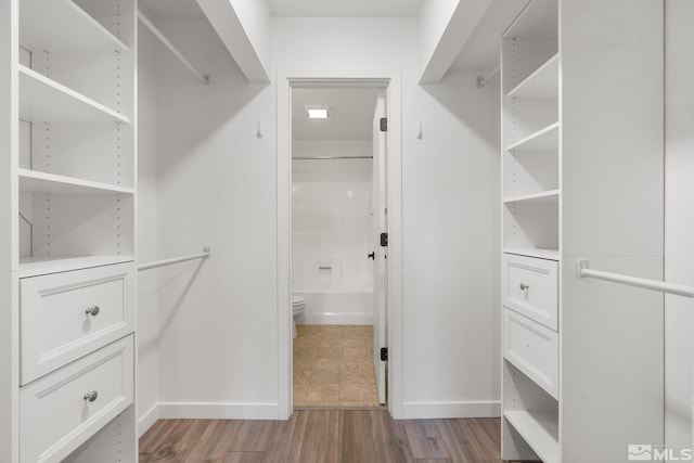 walk in closet with light hardwood / wood-style floors