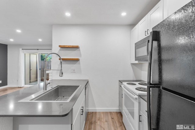 kitchen with black refrigerator, sink, light wood-type flooring, white electric stove, and white cabinets