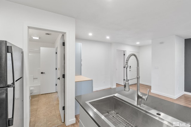 kitchen with sink, stainless steel fridge, and light wood-type flooring