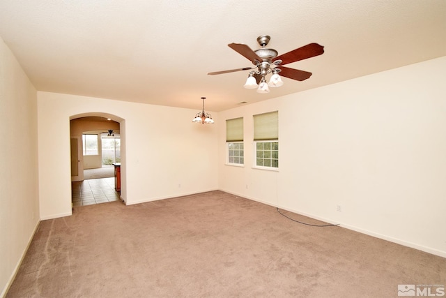 empty room featuring ceiling fan with notable chandelier and carpet