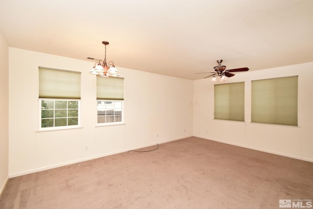 carpeted spare room with ceiling fan with notable chandelier