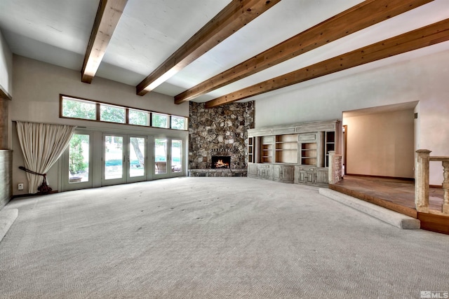 unfurnished living room featuring a stone fireplace, beam ceiling, and carpet